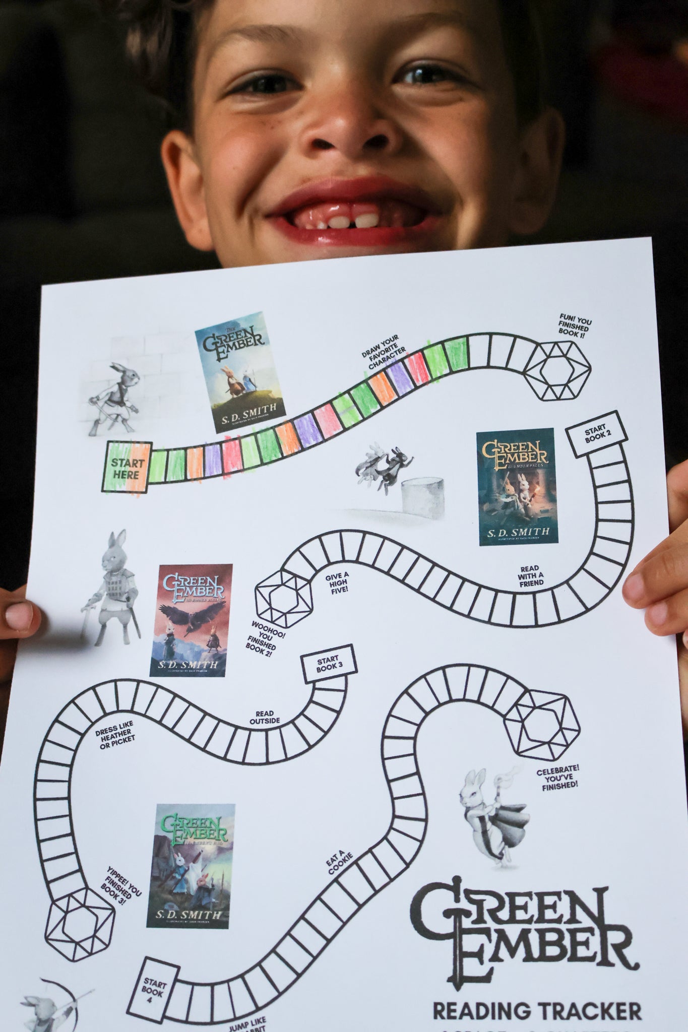 Child holding a 'Green Ember' reading tracker chart