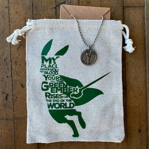 Necklace with pendant on a drawstring bag with green rabbit design and text.